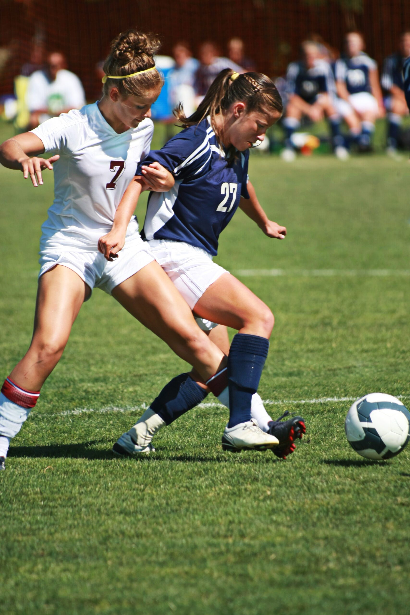 Soccer players tangle battling for ball.